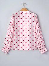 A pink and white stripe textured heart print blouse with long flounce sleeves and ruffled cuffs