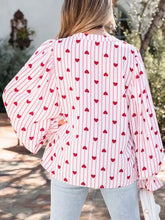 Pink blouse with stripe textured heart print featuring puffy sleeves and a ruffled hem in vertical stripes