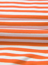A close-up of a soft orange and white striped long sleeve casual sweatshirt fabric with smooth texture