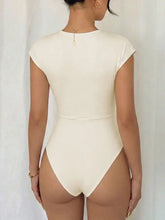 Cream-colored surplice cap sleeve bodysuit featuring a form-fitting one-piece design with short sleeves and high-cut legs