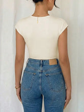 A pair of high-waisted blue denim jeans with a tan leather patch shown from the back paired with a surplice cap sleeve bodysuit