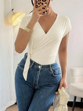 White short-sleeved surplice cap sleeve bodysuit with v-neckline and tied waistband for elegant layering