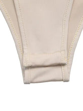 Beige ribbed fabric bikini bottom with stitched trim and seam detailing paired with sweetheart neck balloon sleeve bodysuit