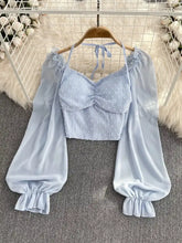 Light blue Swiss dot flounce sleeve blouse with puffy long sleeves and ruffled cuffs displayed on wooden hanger