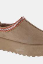 Tan platform slip-on boots with embroidered trim and 2-inch heel height