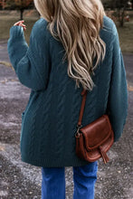 Teal cable knit oversized cardigan with wooden buttons, pockets, and brown leather crossbody bag