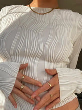 A white textured long sleeve fitted blouse with a wavy pleated design and high neckline