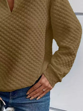 A tan textured notched raglan sleeve sweatshirt with v-neckline and diamond stitching in slightly stretchy material