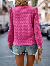 A vibrant pink textured blouse with slightly stretchy knit and puffed shoulders in a round neck long sleeve design