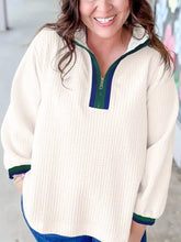 Cream-colored textured waffle knit quarter-zip sweatshirt with green and navy blue trim and slightly stretchy fabric