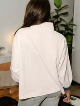 Textured waffle knit half-zip sweatshirt in off-white with high collar and contrasting blue-green cuffs, slightly stretchy