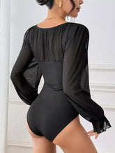 Black flounce sleeve bodysuit with sheer ruched long sleeves and a mesh panel at the back view