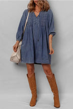 Blue mini denim dress with v-neckline, gathered sleeves, tie neck, and slightly stretchy fabric detail