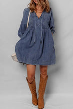 Medium blue mini denim dress with relaxed fit long sleeves and slightly stretchy tie neck drawstring neckline