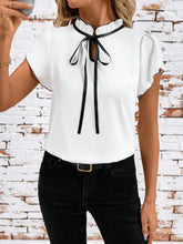 White tie neck short sleeve blouse with black ribbon tie at neckline and sheer short sleeves