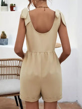 Beige tie shoulder romper with bow details and rolled cuffs
