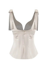 A sleek off-white white satin tie shoulder cami with a plunging neckline and adjustable ribbon straps