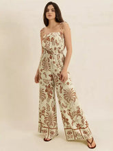 Woman in tie strap wide leg jumpsuit with cream botanical bird patterns