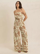 Woman in tie strap wide leg jumpsuit with cream botanical bird pattern