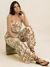 Woman in tie strap wide leg jumpsuit with cream floral patterns