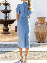 A light blue short sleeve denim dress with a fitted waist and tied button up front in midi length