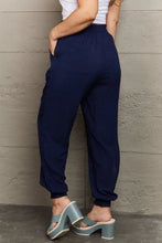 Dark blue tied long joggers with elastic waist, cuffed ankles, pockets