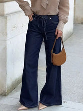 Dark blue high-waisted denim jeans with a tied loose fit flare and drawstring waistband for comfortable wear