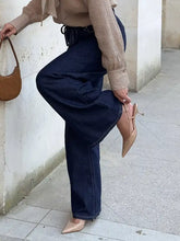 Tan leather shoulder bag with curved minimalist design paired with tied loose fit flare jeans