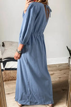 Long light blue denim dress with fitted waist and tied plunge back details suitable for care instructions reference