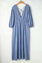 Soft blue denim dress with tied plunge v-neckline and tie-back detail, featuring three-quarter sleeves and care instructions