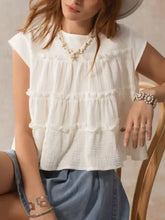 White tiered cap sleeve blouse made of lightweight textured fabric with delicate ruffles and a relaxed fit