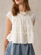 White tiered cap sleeve blouse with ruffle design made of lightweight cotton fabric perfect for warm weather