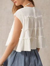 White tiered cap sleeve blouse with ruffled short sleeves and lightweight soft fabric featuring delicate pleated tiers