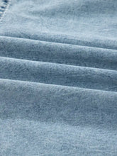 Tiered flowy overall denim dress made of light-wash denim fabric with soft faded blue hue and machine wash care instructions