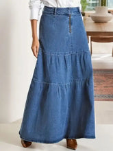 A medium-wash maxi denim skirt with tiered ruffles and a front zipper detail in denim material