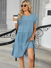 A light blue denim dress with tiered ruffles and a relaxed fit featuring a tiered round neck short sleeve design