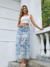 A tiered ruffle denim patchwork skirt in light blue with a tie waist design and frayed hem detailing
