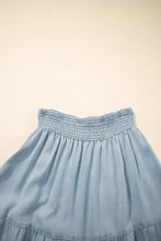 Light blue denim maxi skirt with a smocked waistband and subtle ruffled hem in tiered wash denim material