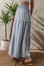 Light blue tiered denim maxi skirt with smocked elastic waistband and soft flowing fabric for comfortable wear