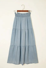 A light blue tiered denim maxi skirt with elastic smocked waistband made of soft cotton fabric
