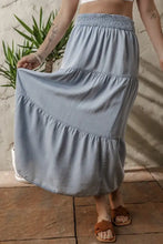 Light blue tiered denim maxi skirt with elastic smocked waistband and soft flowing fabric for comfortable wear