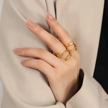 Womans hand with gold abstract rings in titanium steel layered wrap ring