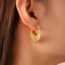 Gold-toned titanium steel leaf shape earring on ear