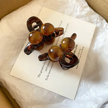 Two tortoiseshell acrylic hair claw clips with spherical accents