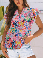 A vibrant short-sleeved blouse with tropical floral print, notched neck, and ruffled sleeves in colorful tones