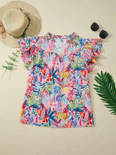 A vibrant short-sleeved blouse with tropical floral print and notched neck in pink, blue, green, and yellow shades