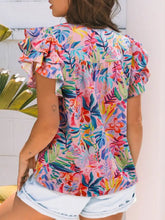 A tropical floral print frilly notched neck blouse with ruffled short sleeves in bold pink, blue, green, and red patterns
