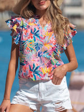 A vibrant tropical floral print frilly blouse with notched neck and ruffled short sleeves on a light background