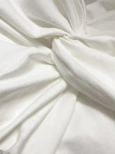 A white long sleeve bodysuit made of soft fabric with a smooth texture and subtle sheen featuring a twist front design