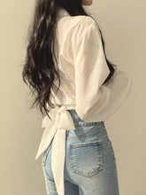 White twisted front long sleeve shirt with puffed sleeves and tied-back waistband shown from the back side